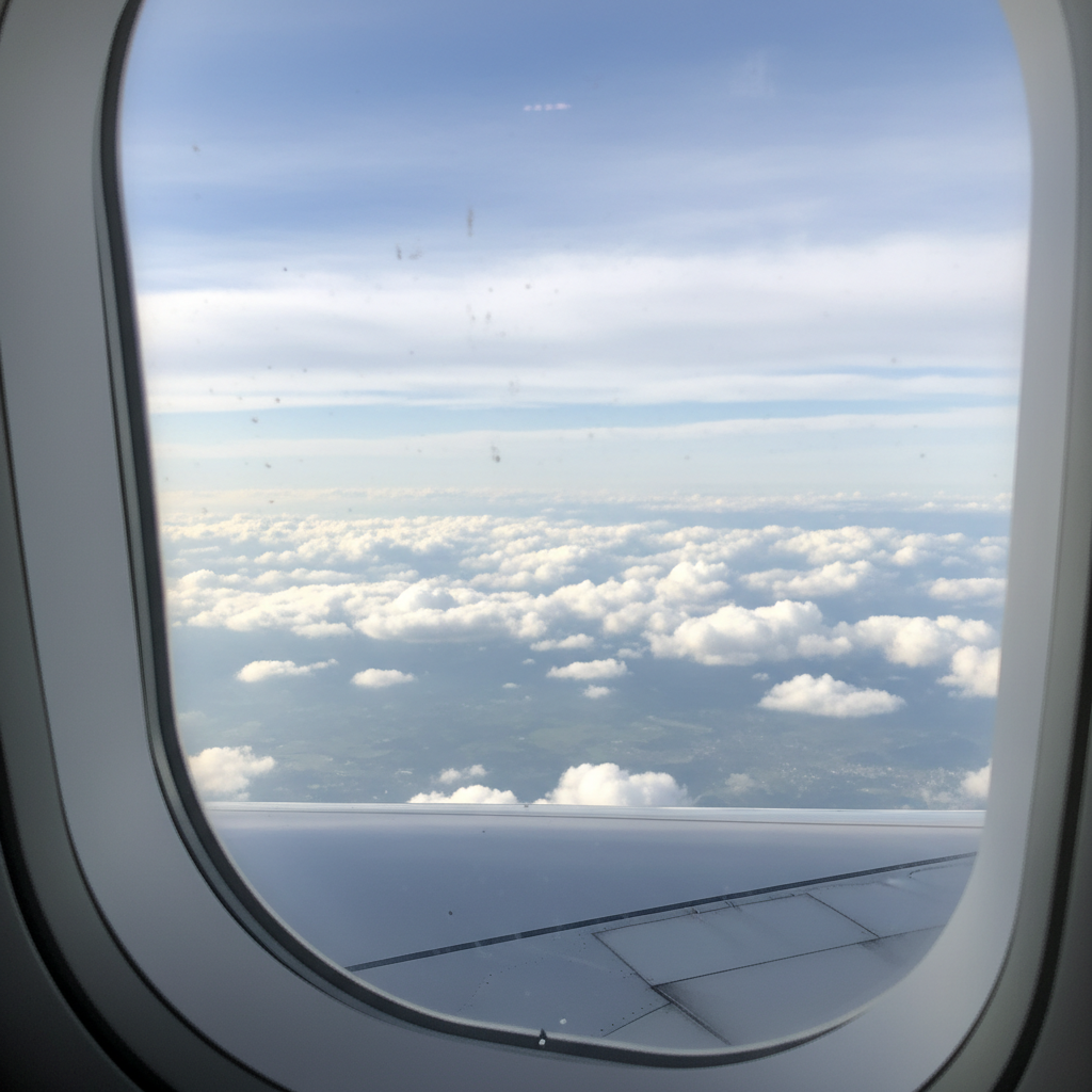 비행기 창문 너머로 보이는 푸른 하늘과 흰 구름